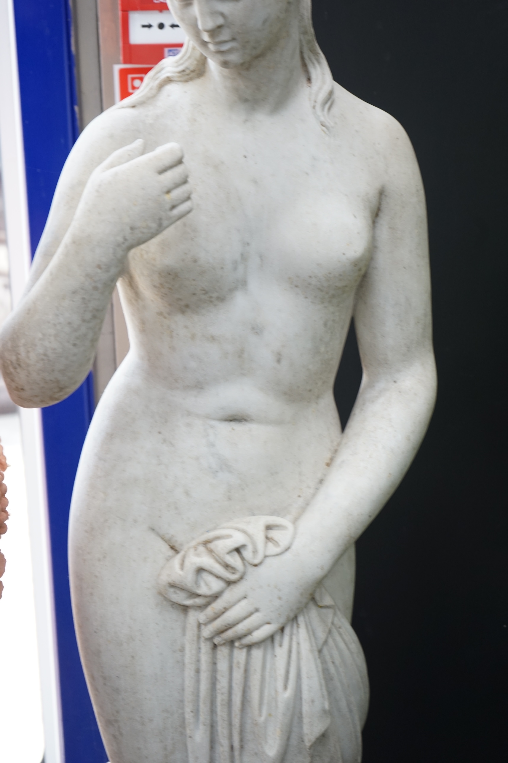 After the Antique. A large carved reconstituted marble figure of Venus, standing beside a tree trunk, 141cm high